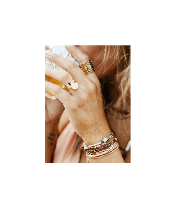 Bracelet sur lequel sont enfilées des pierres naturelles et des boules en acier doré.