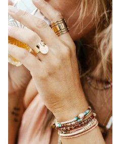 Bracelet sur lequel sont enfilées des pierres naturelles et des boules en acier doré.